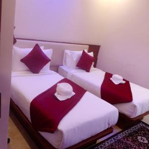two beds in a room with purple and white pillows at Villa Grand Hotel Near Kempegowda International Airport in Bangalore