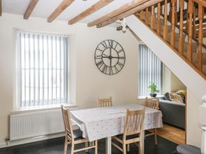 een eetkamer met een tafel en stoelen en een klok aan de muur bij 1 Greenswood Court in Brixham