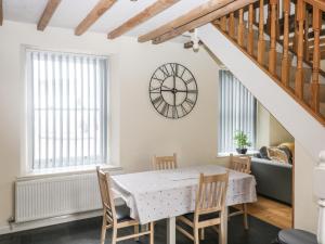 a dining room with a table and chairs and a clock on the wall at 1 Greenswood Court in Brixham