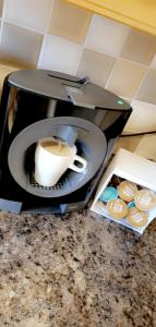 een koffiezetapparaat met een kopje koffie en een bord bij The TJ Rooms in Upton