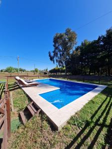 a swimming pool with blue water in a park at Cabañas la soñada in Chascomús