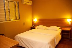 1 dormitorio con 1 cama blanca grande y 2 almohadas en Hotel Bernal, en Ituiutaba