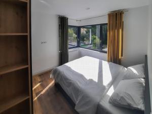een slaapkamer met een wit bed en een raam bij Royal Maison Apartments in Cluj-Napoca