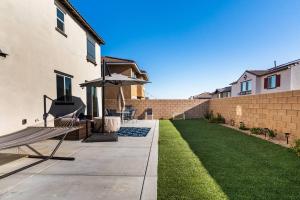 a patio with a bench and an umbrella and a lawn at Spacious Modern Home in Sierra Lakes Fontana in Fontana