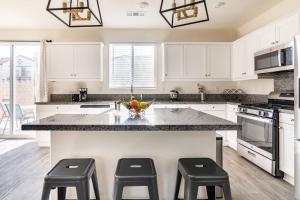 a kitchen with white cabinets and a counter with stools at Spacious Modern Home in Sierra Lakes Fontana in Fontana