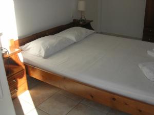 a bed with a wooden frame and white sheets at Giorgos Apartments in Palaiochora