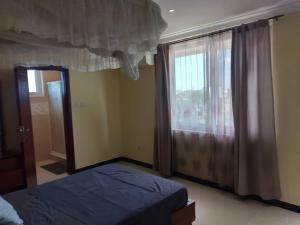 1 dormitorio con cama y ventana grande en Bay's view, en Dar es Salaam