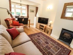ein Wohnzimmer mit Couch und Kamin in der Unterkunft Lilac Cottage in Windermere