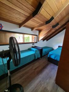 a room with two beds and a fan at La casa de Hostal del Sol in Rosario