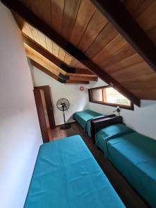 ロサリオにあるLa casa de Hostal del Solの緑のベッド2台と窓が備わる客室です。