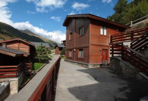 une maison en bois avec un chemin à côté d'un bâtiment dans l'établissement PORT DRET Peu del Riu 202 - Vall d'Incles - Soldeu, à Incles