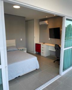 ein Schlafzimmer mit einem Bett, einem Schreibtisch und einem Fernseher in der Unterkunft Casa Blanca Hibiscus Angra de Ipioca Maceió in Maceió + 20 Fotos