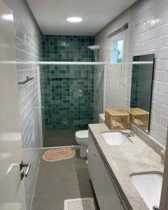 ein Badezimmer mit zwei Waschbecken, einer Dusche und einem WC in der Unterkunft Casa Blanca Hibiscus Angra de Ipioca Maceió in Maceió