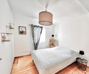 a white bedroom with a bed and a window at Villa 2 chambres Netflix - Wifi - Parking - Terasse in Ruelle-sur-Touvre