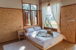 a bedroom with a bed in a room with a window at Baanfanglamoon in Ban Mae Mao