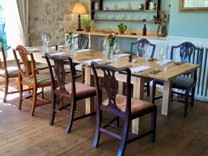 a wooden table with chairs and a long table with glasses at Farthings Country House Hotel & Restaurant Tunton in Taunton