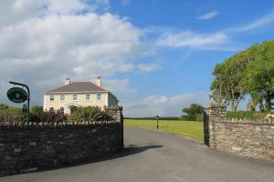 una casa bianca con un muro di pietra e un cancello di Springfield House B&B a Clonakilty