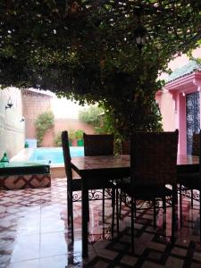 a table and chairs under a tree with a pool at Villa Eden in Ouarzazate