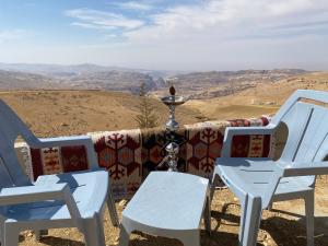 two white chairs and a couch with a view at Nabati hostel in Wadi Musa