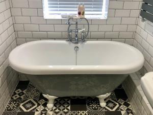 a bath tub in a bathroom with a window at Farthings Country House Hotel & Restaurant Tunton in Taunton