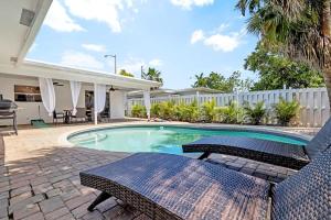 a swimming pool with two chairs next to a house at NEW! 3b/2ba: pool, hot tub, and cotton candy maker in Fort Lauderdale