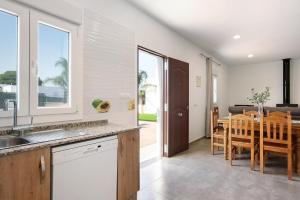 una cucina e una sala da pranzo con tavolo e sedie di Villa Montenmedio - Carmelo a El Soto