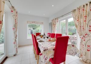 uma sala de jantar com uma mesa e cadeiras vermelhas em Forest Lodge em Southwold