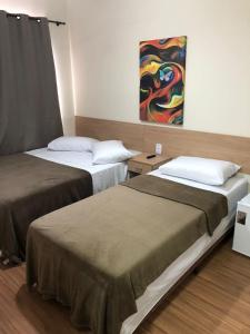 two beds in a room with a painting on the wall at Pousada HD in Nova Friburgo