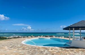 a swimming pool with the ocean in the background at OceanBlue Resort in Christ Church