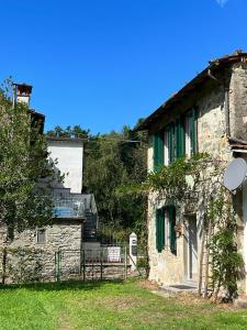 an old stone building with green shutters on it at La Casina del Bassotto in Bagni di Lucca
