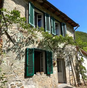 a building with green shutters and a window at La Casina del Bassotto in Bagni di Lucca
