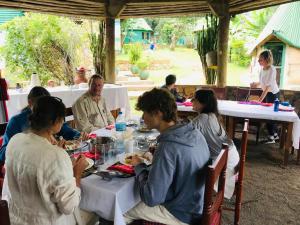 Songota Falls Lodge في أروشا: مجموعة من الناس يجلسون على طاولة يأكلون الطعام