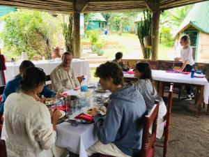 阿魯沙的住宿－Songota Falls Lodge，一群坐在餐桌上吃食物的人