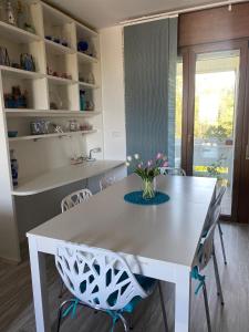 tavolo bianco da pranzo con sedie e vaso di fiori di Sisters'House a Lido