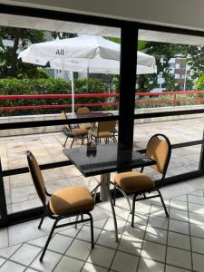 a table and chairs with an umbrella on a balcony at Flat - Navegantes Residence Hotel in Recife