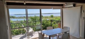 ein Balkon mit Tisch und Stühlen und einem großen Fenster in der Unterkunft Casa vista al Rio Parana Vuelta de Obligado in San Pedro