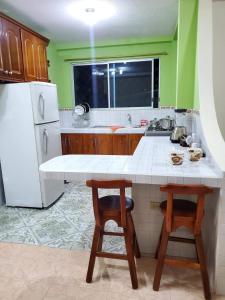 La cuisine est équipée d'un comptoir blanc et d'un réfrigérateur. dans l'établissement Departamento Puyo Fantastic., à Puyo