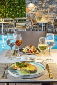 una mesa con un plato de comida y copas de vino en Mystery Skiathos Luxury Residence, en Skiathos