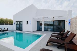 a swimming pool with chairs and a house at Villa Etoile in Ayios Kirikos