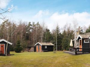 a group of small buildings in a field with trees at Holiday home MUNKA-LJUNGBY III in Munka-Ljungby