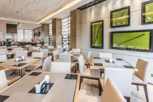 a restaurant with tables and chairs and a tv at Somerset Grandview Shenzhen in Shenzhen