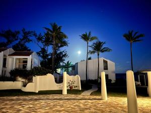 a house with palm trees and a white fence at OceanBlue Resort in Christ Church