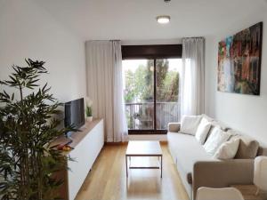 Una sala de estar con un sofá blanco y un televisor. en Apartamento amplio, luminoso y confortable CC, en Madrid