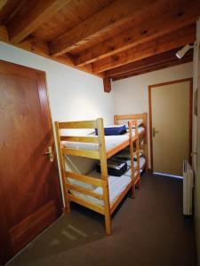 two bunk beds in a room with a door at Logement 6 pers au cœur des montagnes pyrénéennes in Boutx