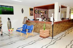 un bar con sillas azules y TV en una habitación en Hôtel Printemps Mont Korhogo, en Korhogo