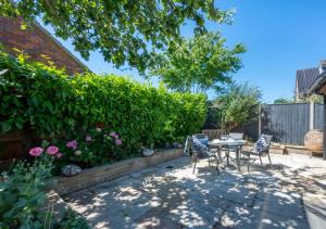 a patio with a table and chairs in a garden at Pippins Lodge in Holt