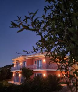 Casa grande de color rosa con balcón por la noche en Julietta Suites, en Argostoli