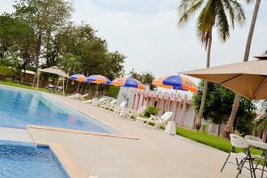 a swimming pool with umbrellas and lounge chairs and a pool at Hôtel Printemps Mont Korhogo in Korhogo