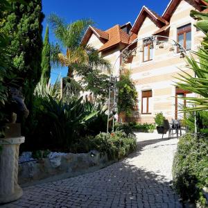 une maison avec un chemin pavé devant un bâtiment dans l'établissement Chalet Vitorino, à Sintra