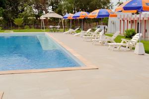 a swimming pool with lounge chairs and umbrellas at Hôtel Printemps Mont Korhogo in Korhogo